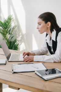 Femme d'affaires utilisant un ordinateur portable dans un espace de bureau moderne avec des documents et de la technologie.