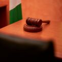 Gavel en bois posé sur une table, drapeau avec bandes vert et blanc à l'arrière-plan