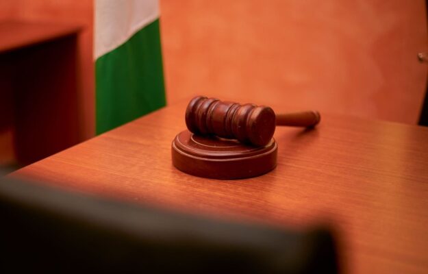 Gavel en bois posé sur une table, drapeau avec bandes vert et blanc à l'arrière-plan