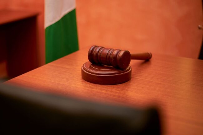 Gavel en bois posé sur une table, drapeau avec bandes vert et blanc à l'arrière-plan