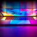 Laptop ouvert sur table, écran affiche un motif arc‑en‑ciel lumineux