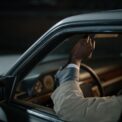 Un homme ajuste un levier à l'intérieur d'une voiture sombre