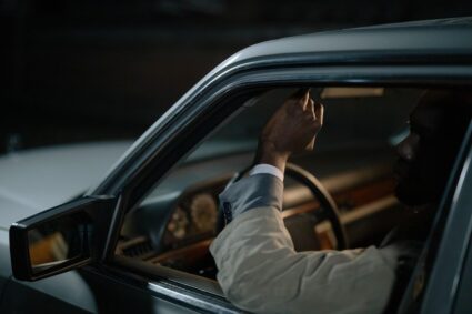 Un homme ajuste un levier à l'intérieur d'une voiture sombre