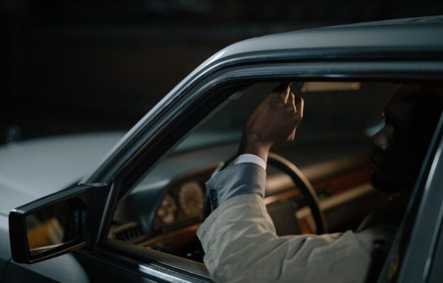 Un homme ajuste un levier à l'intérieur d'une voiture sombre