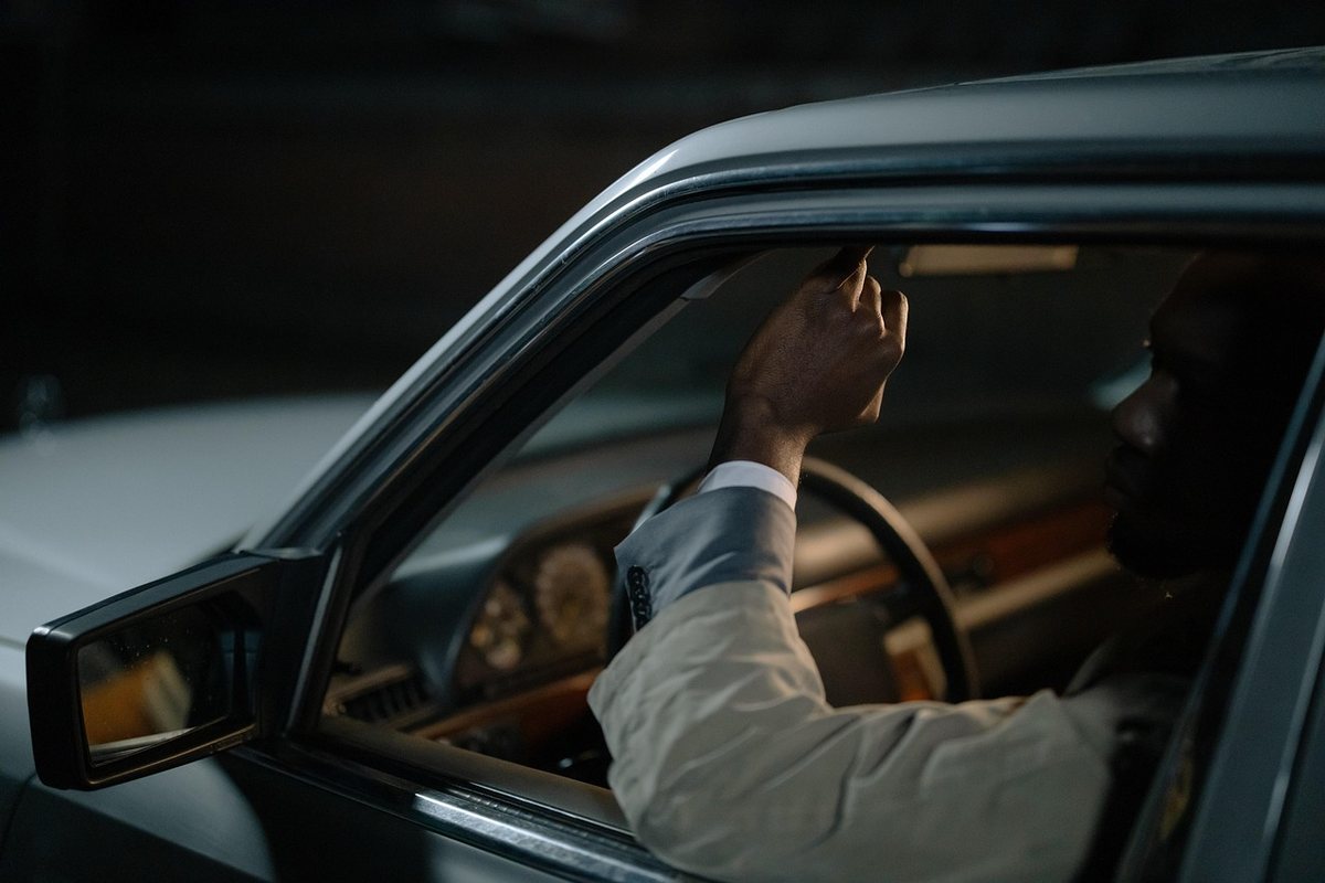 Un homme ajuste un levier à l'intérieur d'une voiture sombre