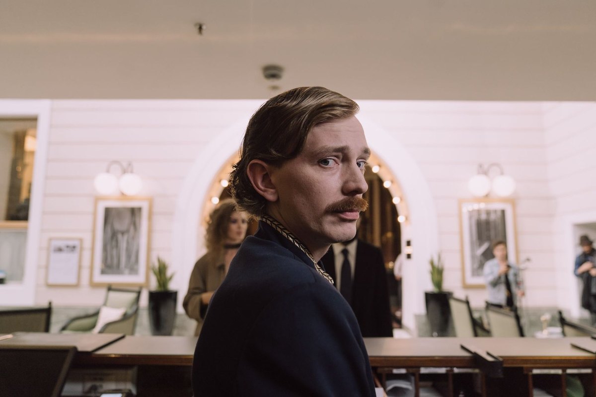 Homme en costume avec moustache dans un salon avec tables et portraits Homme en costume avec moustache dans un salon avec tables et portraits