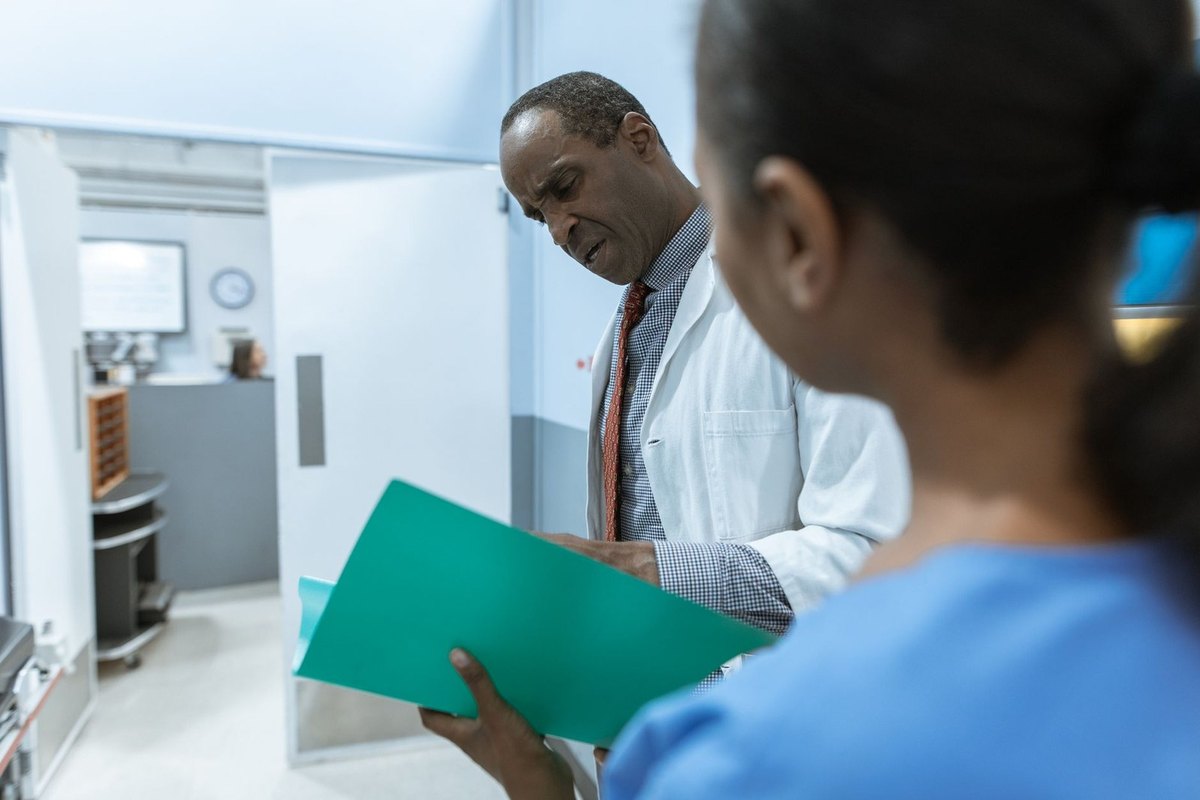 Médecin et infirmière en conversation dans un couloir hospitalier, tenant un dossier