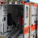 Ambulance avec porte ouverte, rampe déployée, personnel en tenue orange à l'intérieur